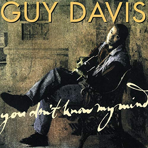 Guy Davis sitting in a chair holding a guitar on a textured album cover.