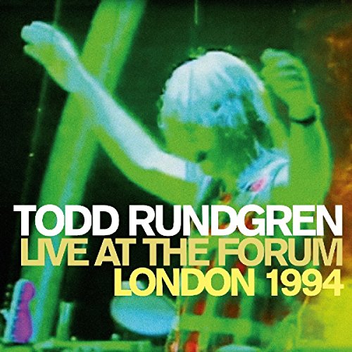 Todd Rundgren performing live on stage with green and yellow lighting.