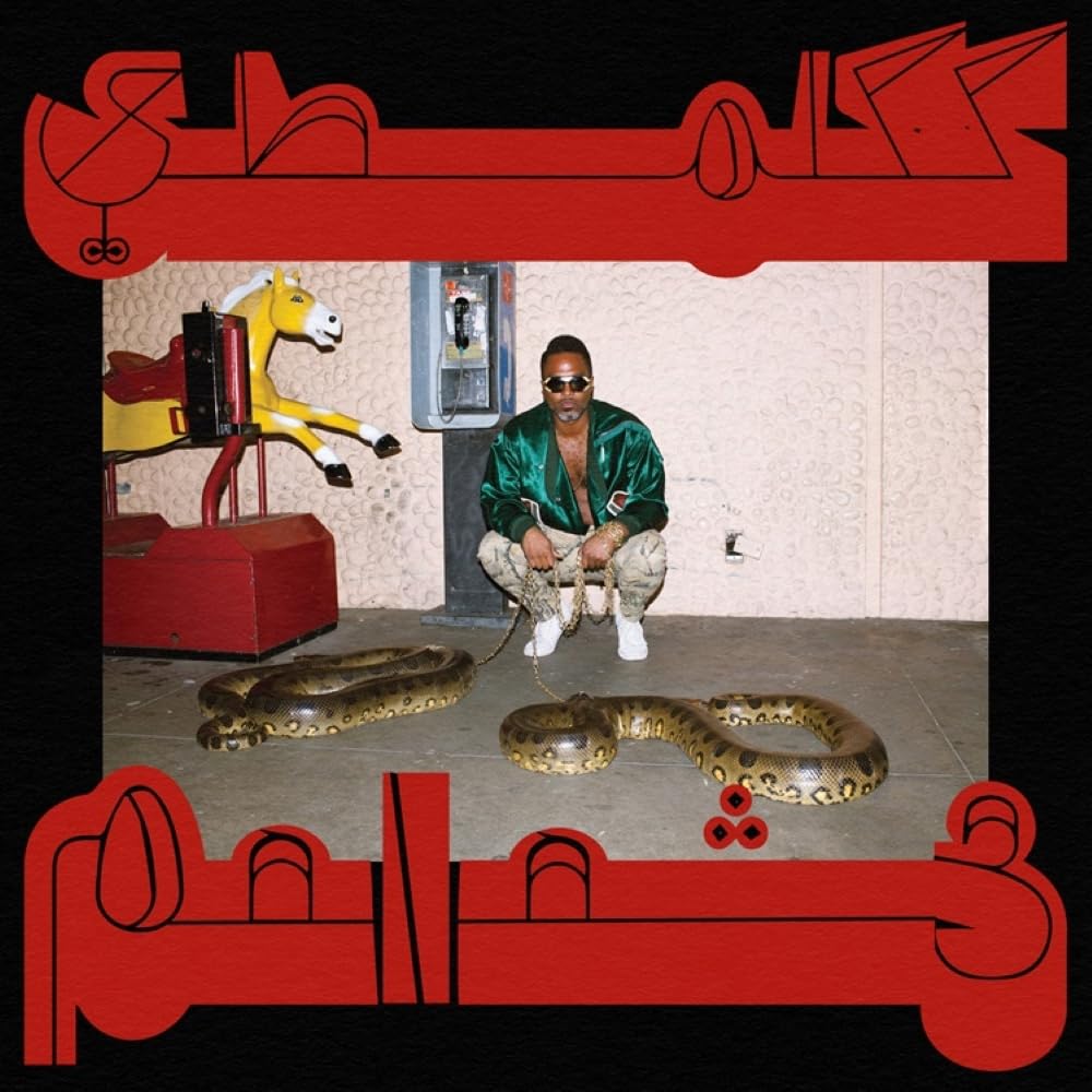 Album cover: man with snake, rocking horse, and red geometric design.