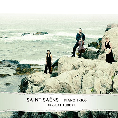 Three musicians with instruments pose on rocky coastline, album cover.