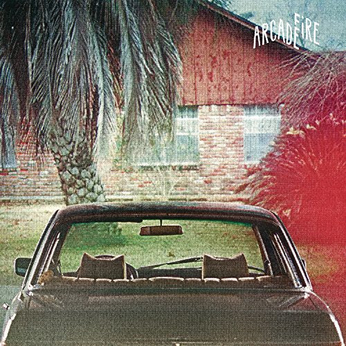 View from behind a car parked in front of a brick house with palm trees.