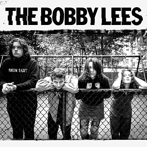 Black and white photo of four people leaning on a chain-link fence.