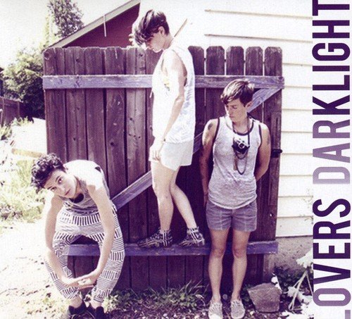 Three people lean against a wooden fence on a CD cover.