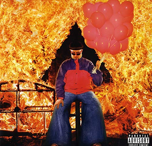 Oliver Tree sits with red balloons before a fiery, dark background.