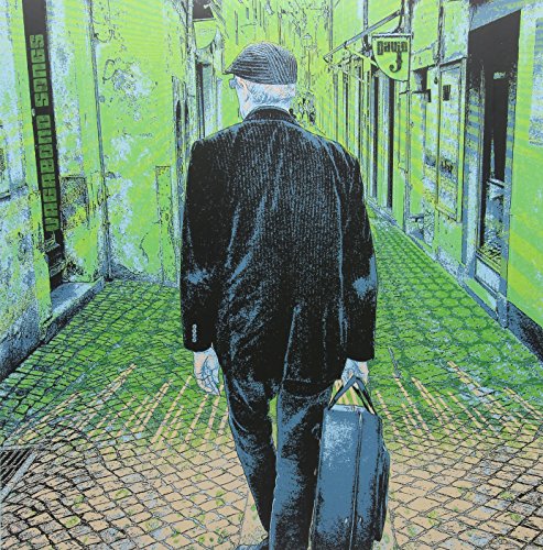 Man in a suit walking away down a narrow, cobbled street.