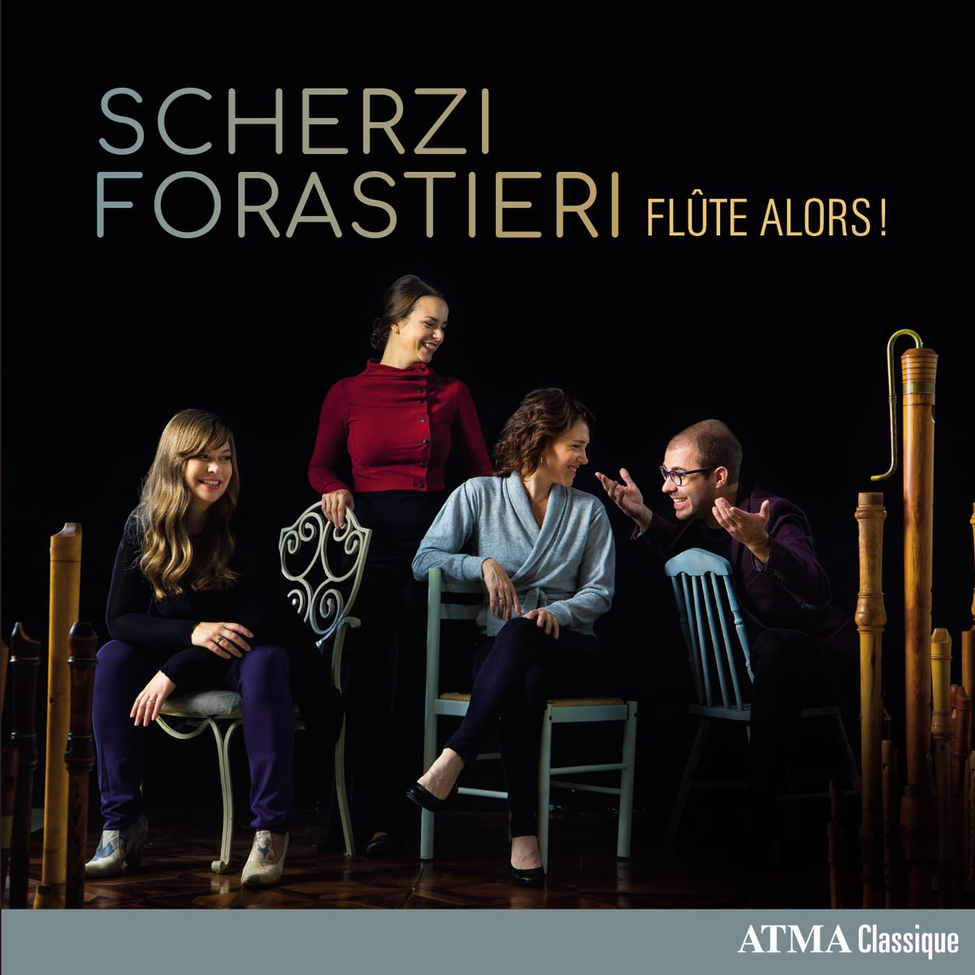 Four musicians with flutes and recorders on a dark stage.