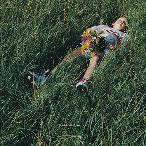 Person lying in tall green grass holding a colorful bouquet.