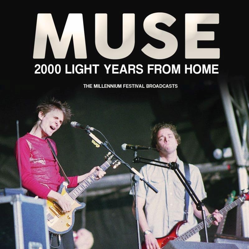 Muse performing live on stage with guitars and microphones under large text headers.