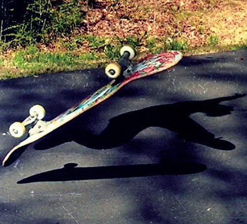Skateboard laying on asphalt with a long, dark shadow.