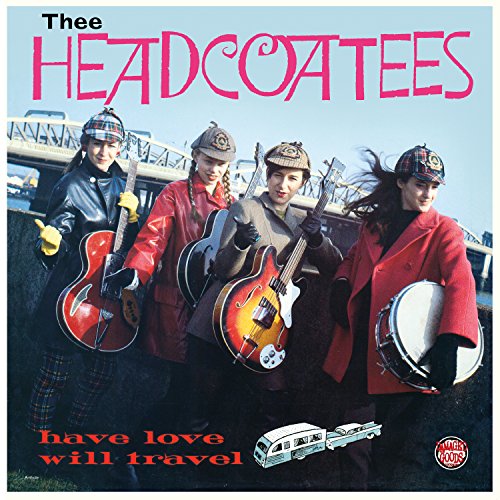 Four women with guitars and a drum, wearing caps and coats.