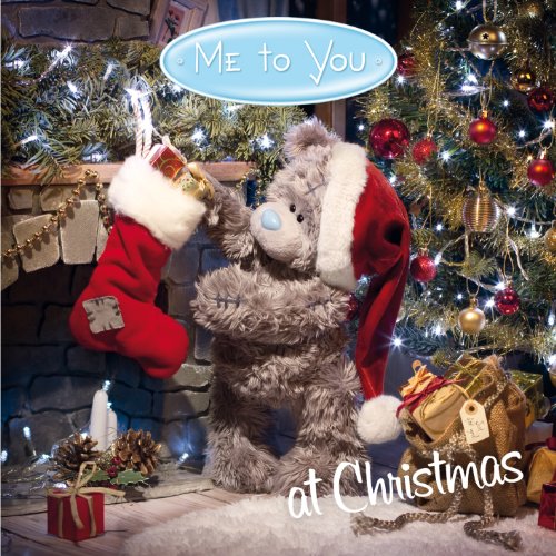 Teddy bear in Santa hat by a decorated Christmas tree and stocking.