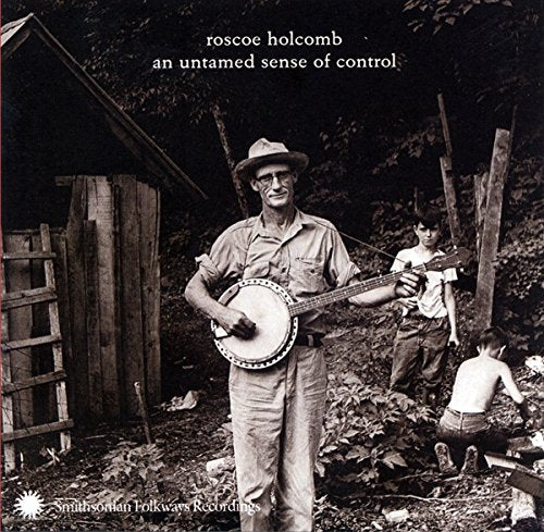 Black and white photo of Roscoe Holcomb playing a banjo with children.