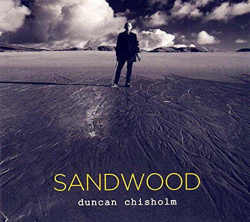 CD cover: man standing on a textured beach under cloudy sky.