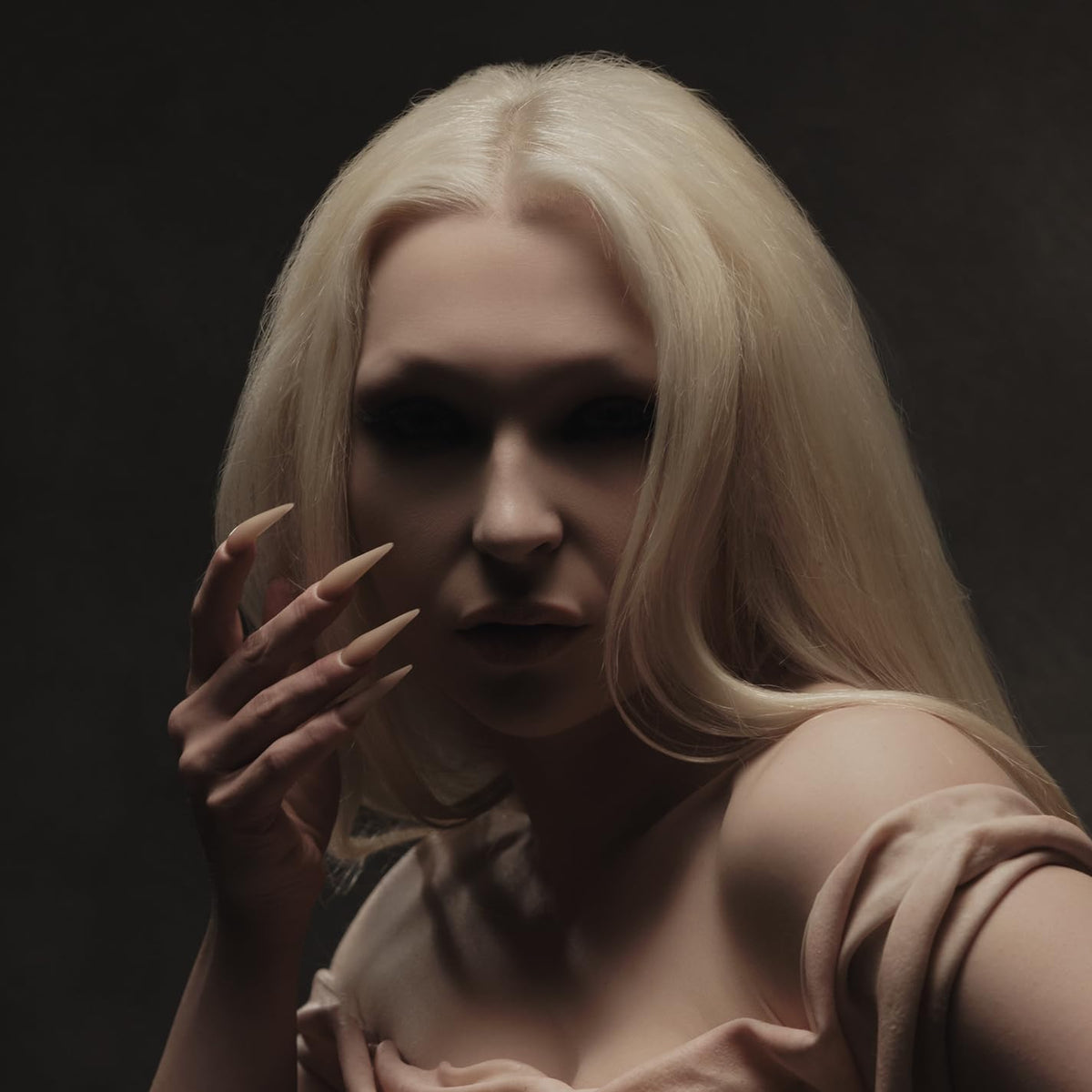 Close-up portrait of a person with long blonde hair and dark nails.