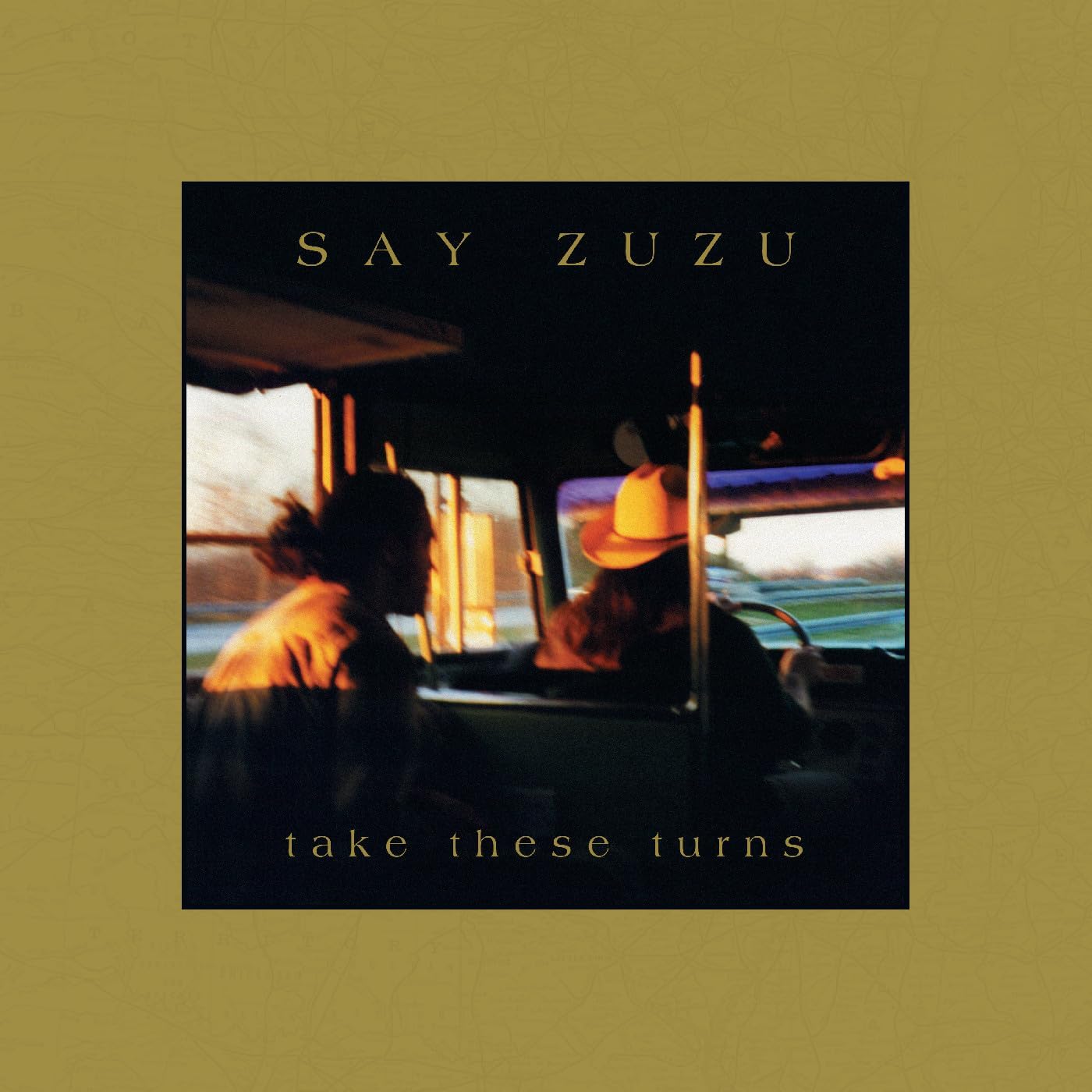 Album cover for Say Zuzu’s “Take These Turns” featuring figures in a vehicle.