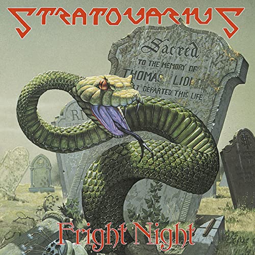 A snake with an open mouth coiled in front of a tombstone in a graveyard.