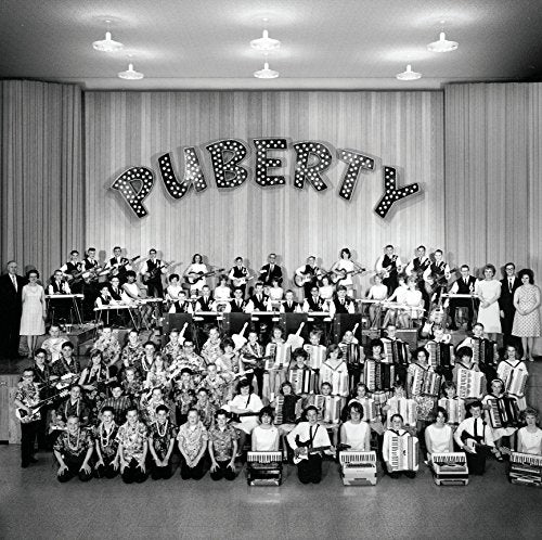 Black and white photo of a large polka band titled "PUBERTY" in lights.