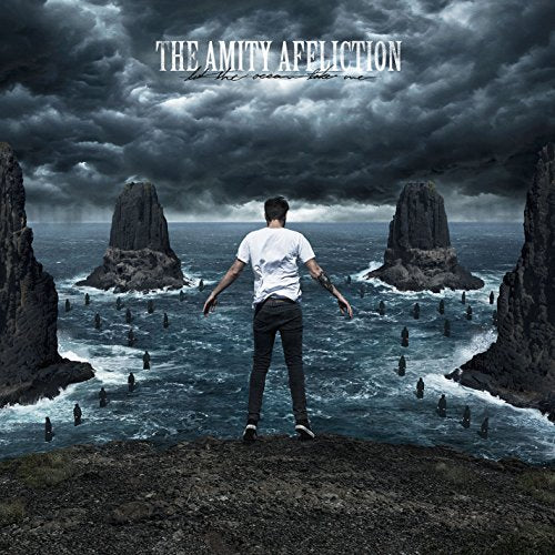 Album cover: man facing ocean rocks under stormy, dark sky.