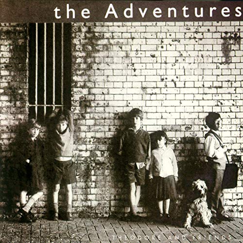 Black and white photo of four children and a dog standing against a brick wall.
