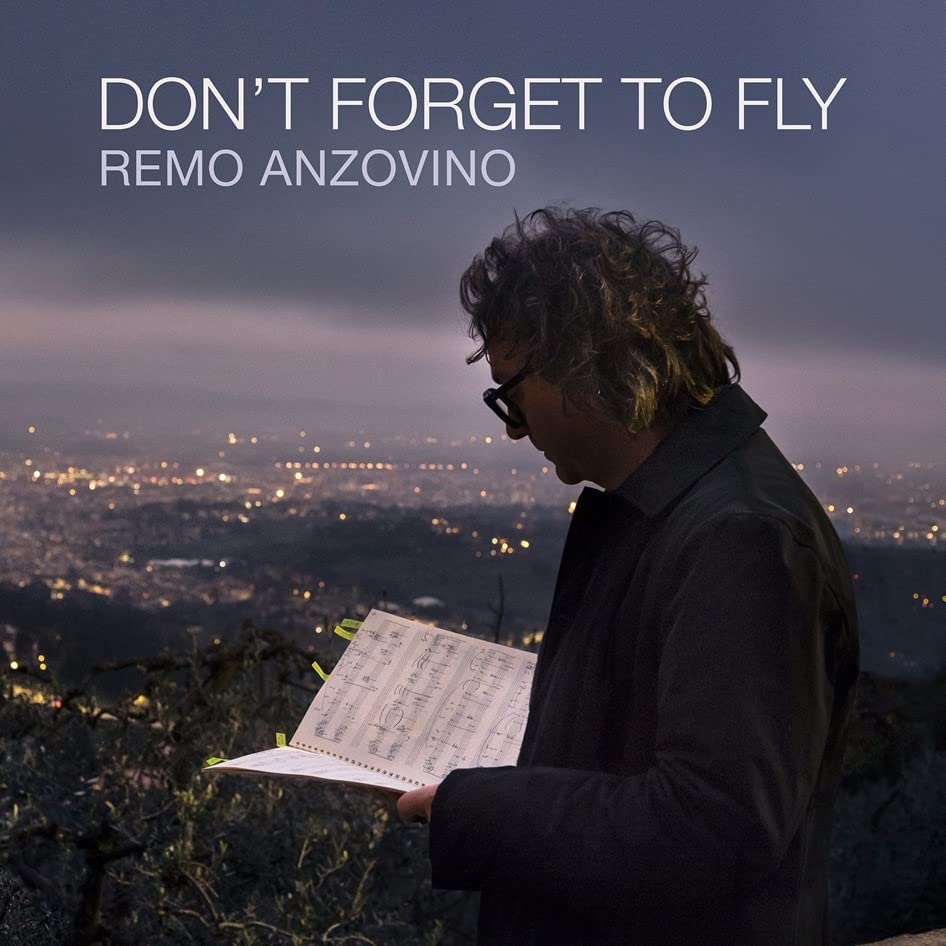 CD cover: Remo Anzovino with sheet music, city lights in background.