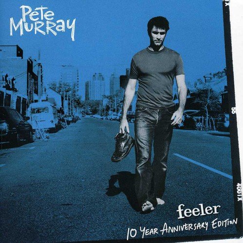 Blue-tinted album cover of Pete Murray walking down a city street holding one shoe.