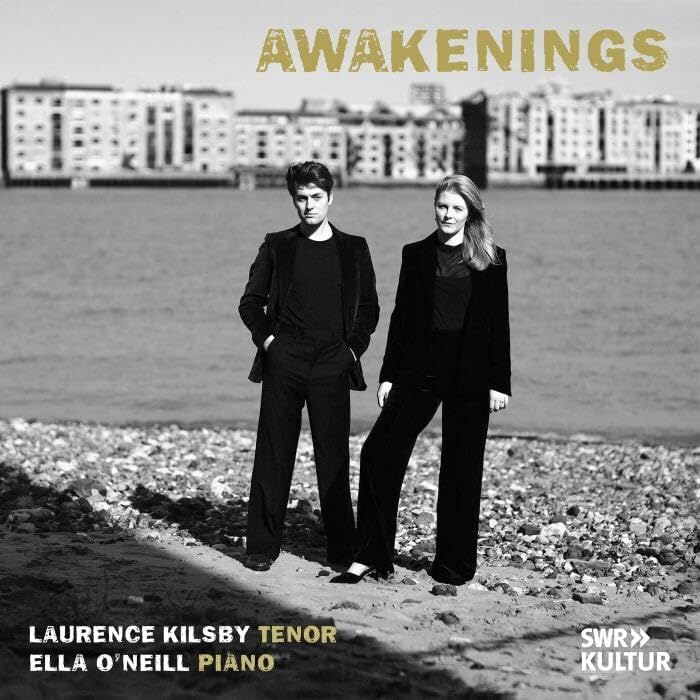 CD cover: two figures on a beach with a city skyline backdrop.