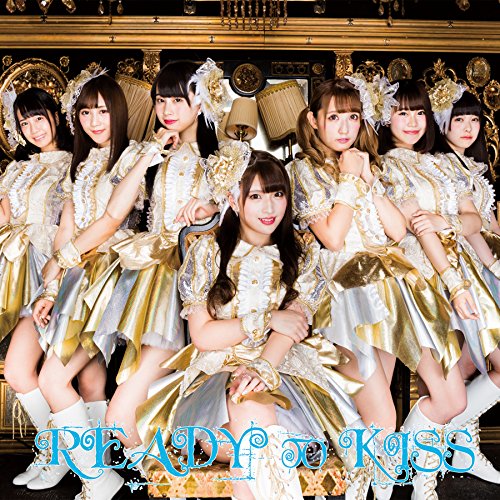 Seven young women in ornate dresses pose with a “Ready to Kiss” logo.