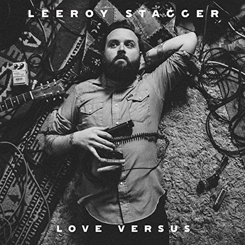 Black and white album cover featuring a bearded man lying with instruments.