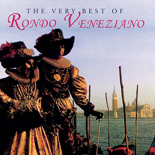Two people in traditional Venetian carnival costumes stand by a canal with Venice behind.