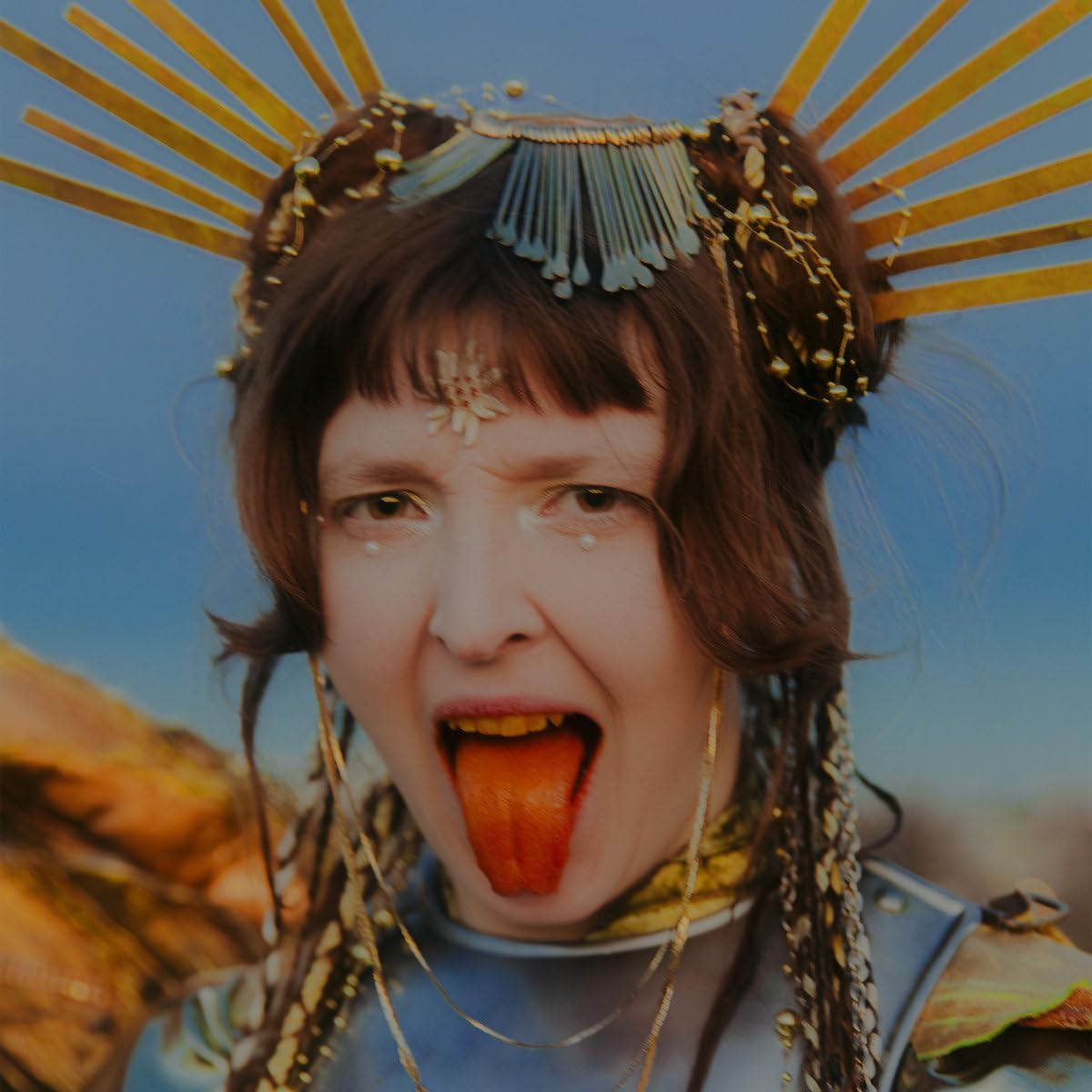 Close-up of a woman with ornate headwear, mouth open, and bright eyes.