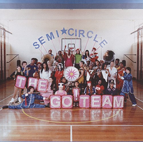Large group posing with lettered blocks in a gymnasium.