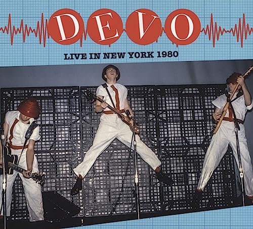 Devo band members in white jumpsuits performing live on stage, 1980.
