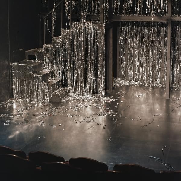 Stage with silver fringe curtains and scattered reflective pieces.