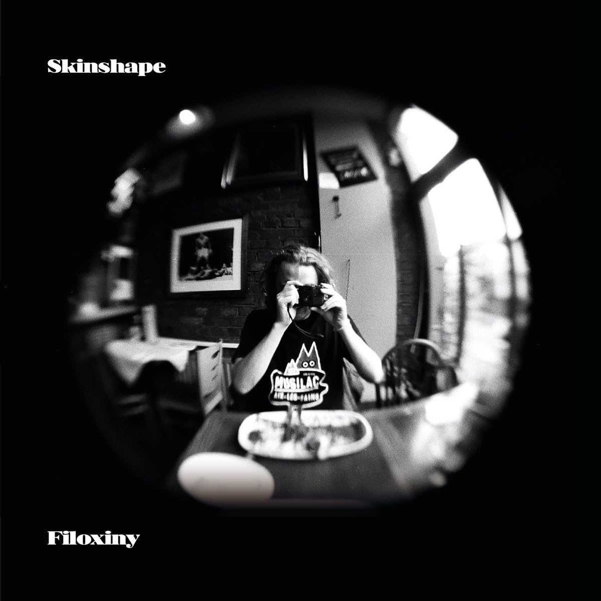 Black and white fisheye view of a person holding a camera.