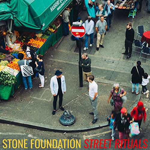 Street scene with people, market stalls, and band name text overlay.