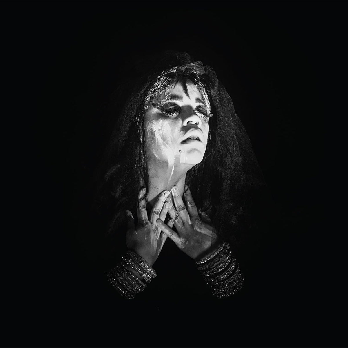 Black and white portrait of a person with dramatic makeup and veil.
