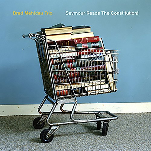 Shopping cart filled with books against a blue wall with white baseboard trim.
