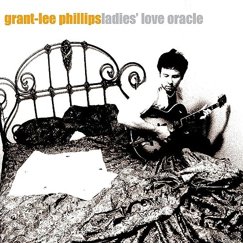 Black and white album cover featuring a man playing guitar in bed.
