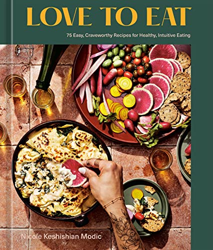 Cookbook cover with colorful food arrangement and a hand serving a slice.