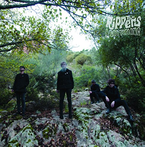 Four people in dark clothing pose amongst trees and rocky terrain.