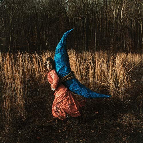Woman in red dress carrying a large blue crescent moon shape.