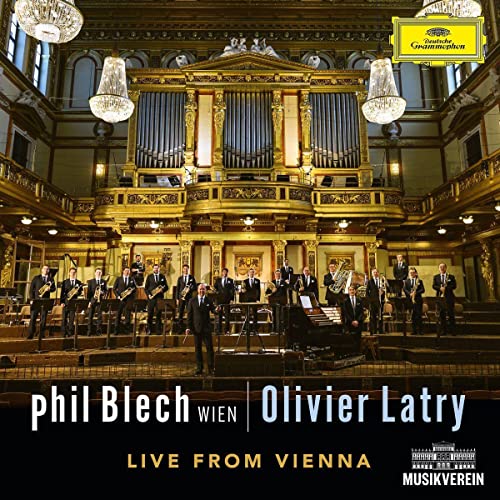 Orchestra performing on stage in a grand, ornate concert hall.