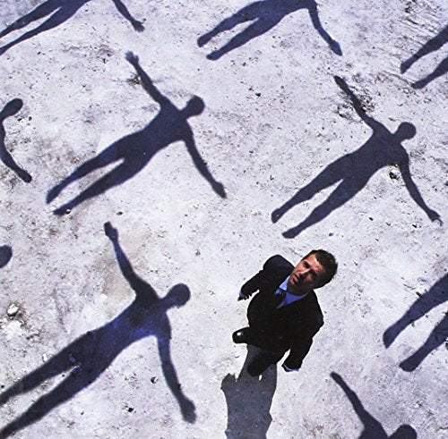 Man in a suit surrounded by long, distorted shadows.