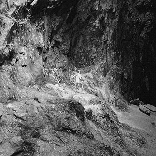 Black and white album cover featuring a person in a rocky cave.