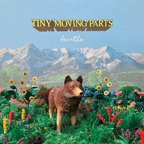 AlbumCLLM album cover featuring a small wolf figurine in a flowery mountainLSPHL mountain landscape.