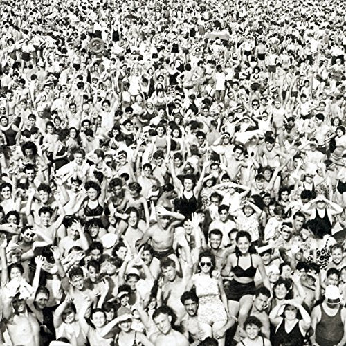 Black and white photo of a large crowd of people with raised arms.