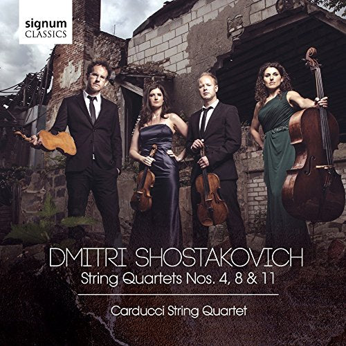 The Carducci Quartet stands in front of a ruined building holding their musical instruments.
