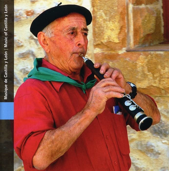 Man playing a black clarinet, stone wall background, CD cover art.