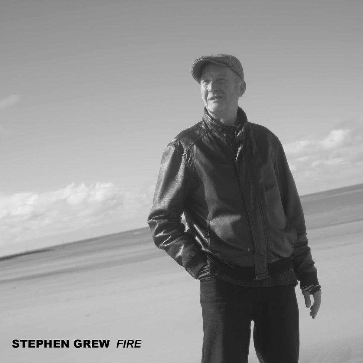 Black and white portrait of Stephen Grew wearing a cap and leather jacket.