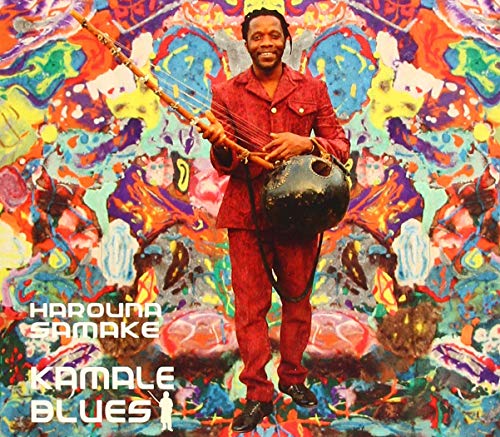 Harouna Samake in red suit playing a kamale ngoni against colorful abstract art.